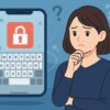 スマホ画面に赤い鍵アイコンが表示され、疑問符が浮かぶ中、不安そうに考える日本人女性が描かれたイラスト