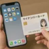 iPhoneを持つ手元とマイナンバーカードをかざしている様子。NFC対応で連携をイメージ。