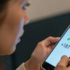 不安な表情の女性が、スマートフォンに表示された「181」と「+181」の不審な着信番号を見つめている画像。