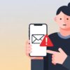 スマートフォンを手に持ち、画面に表示された警告付きのメール通知を慎重に確認している様子のイラスト。東京ガスの迷惑メールやフィッシング詐欺への注意喚起を促すブログ記事のアイキャッチ画像。